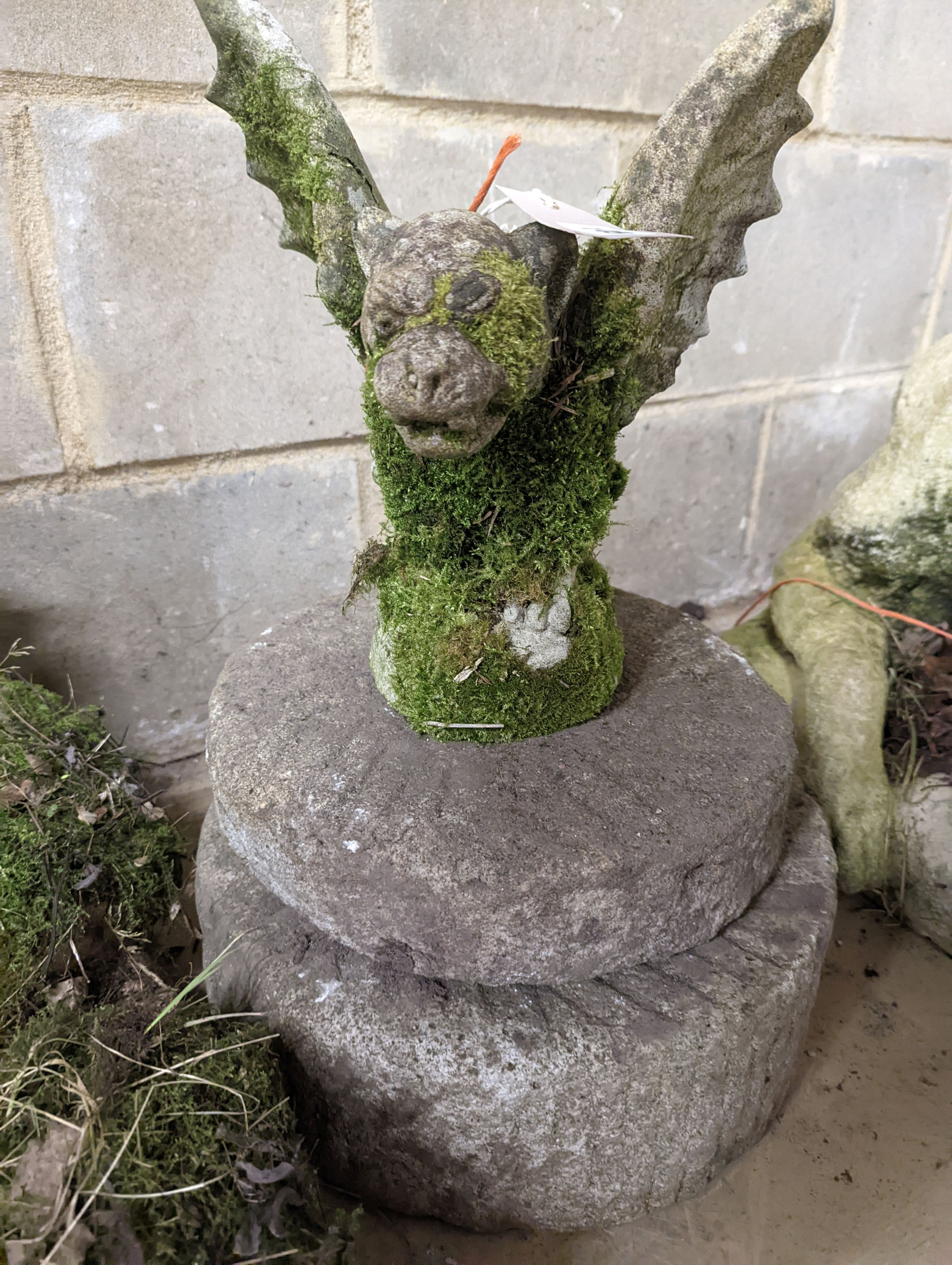 Two small circular mill stones, a reconstituted stone gargoyle and a terracotta reclining pixie garden ornament